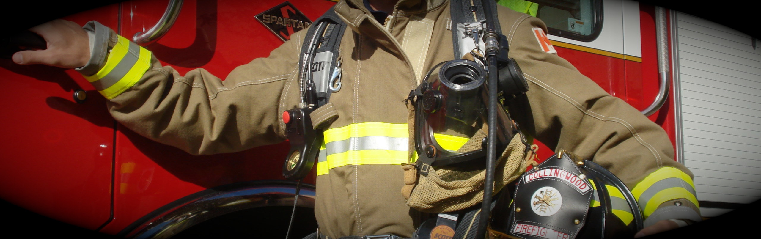 Firefighter with helmet holding door handle of a firetruck